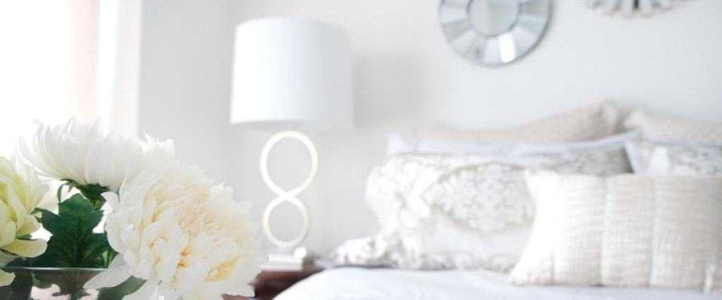 Fresh flowers with layers of textured pillows in a light palette bedroom