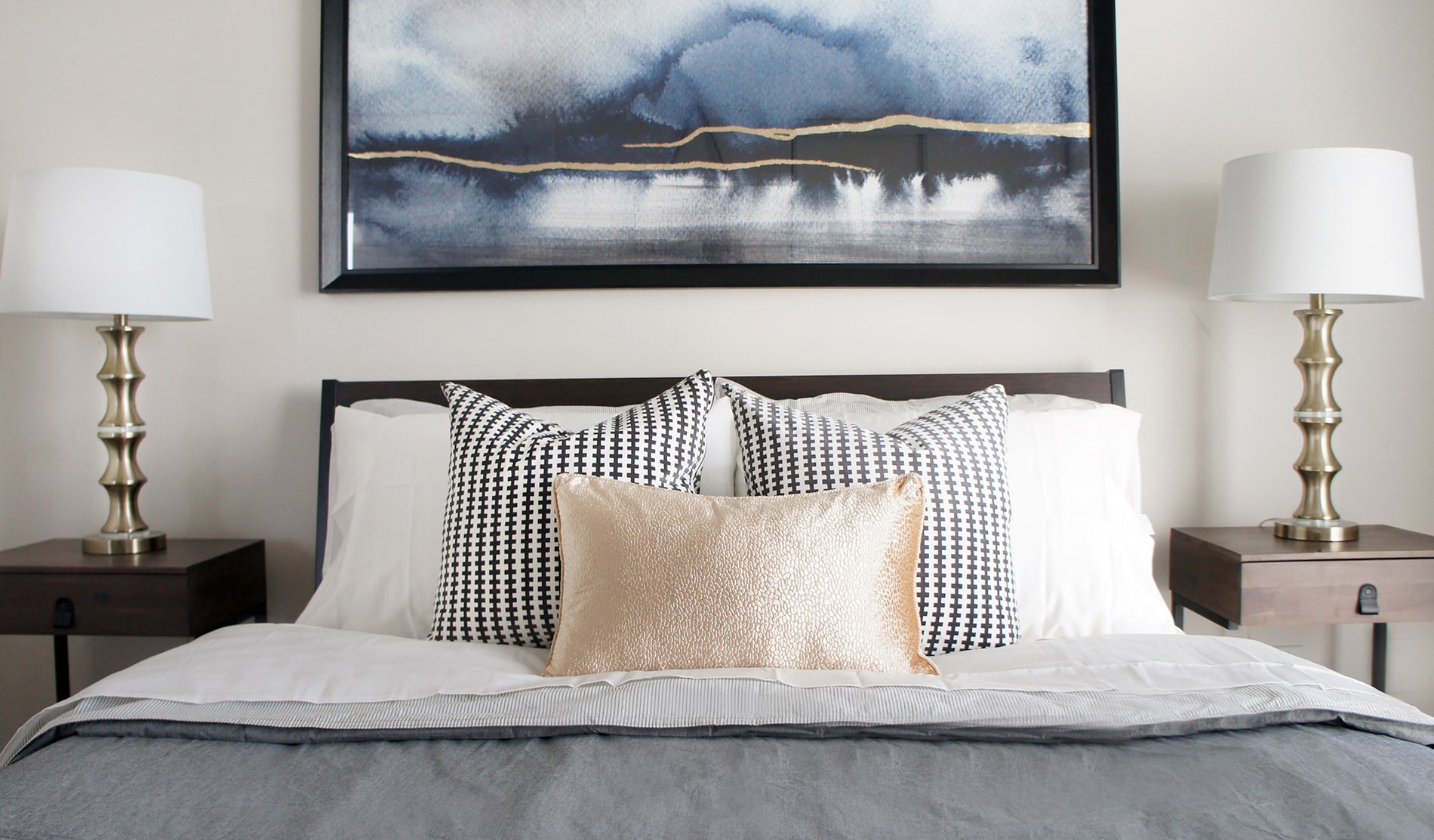 A piece of wall art featuring blue and gold added visual interest and height over the headboard in one of the condo bedroom designs