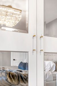 A shimmery chandelier behind glass-panelled bedroom double doors